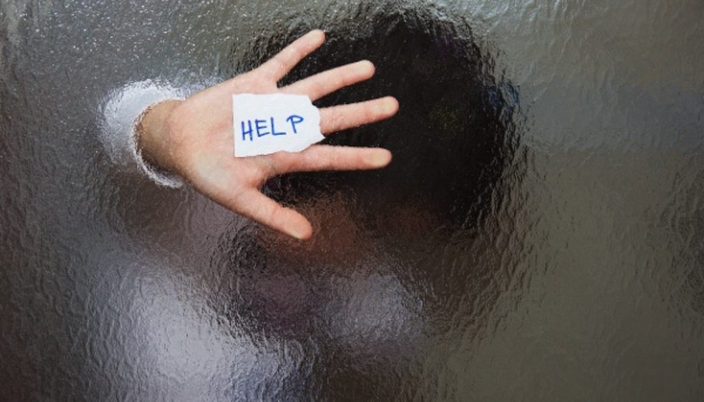 hand pressed against glass holding help written on paper